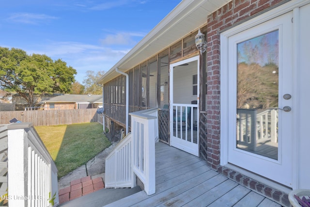 wooden deck with a lawn and a sunroom