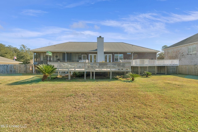 back of house featuring a lawn, a wooden deck, and a sunroom