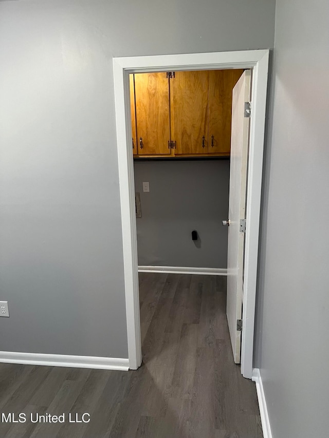 clothes washing area featuring dark wood-type flooring and cabinets