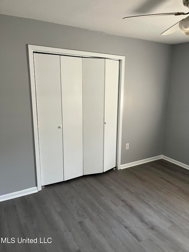 unfurnished bedroom featuring dark wood-type flooring, a closet, and ceiling fan