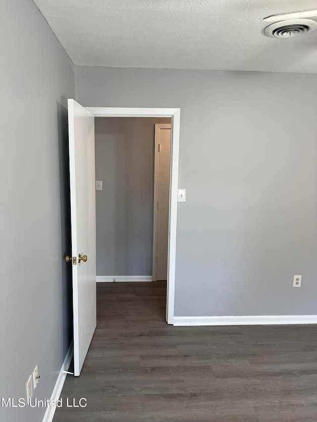 empty room with a textured ceiling and dark hardwood / wood-style flooring