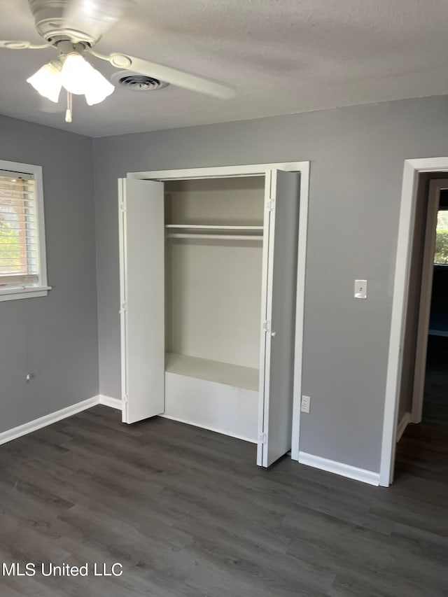 unfurnished bedroom with a closet, ceiling fan, a textured ceiling, and dark hardwood / wood-style floors