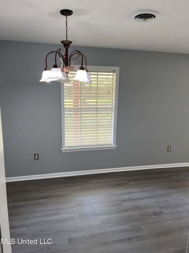 empty room with a notable chandelier and dark hardwood / wood-style floors