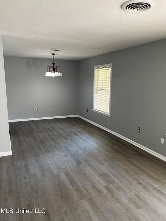 empty room with a chandelier and dark wood-type flooring