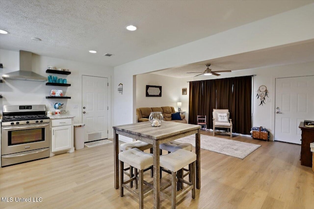 dining area with a textured ceiling, ceiling fan, light wood finished floors, and recessed lighting