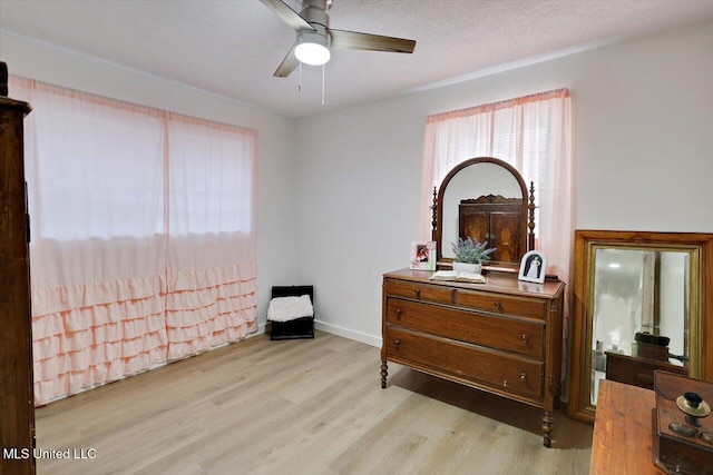 bedroom featuring light wood-style floors, a textured ceiling, baseboards, and a ceiling fan