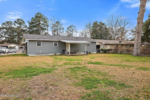 rear view of house featuring a lawn and fence