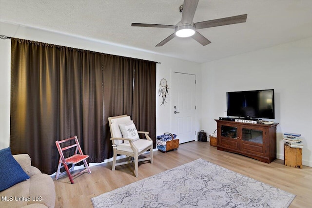 living room with ceiling fan, a textured ceiling, and wood finished floors