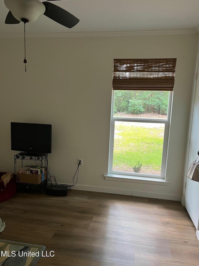 unfurnished living room with baseboards, wood finished floors, and crown molding