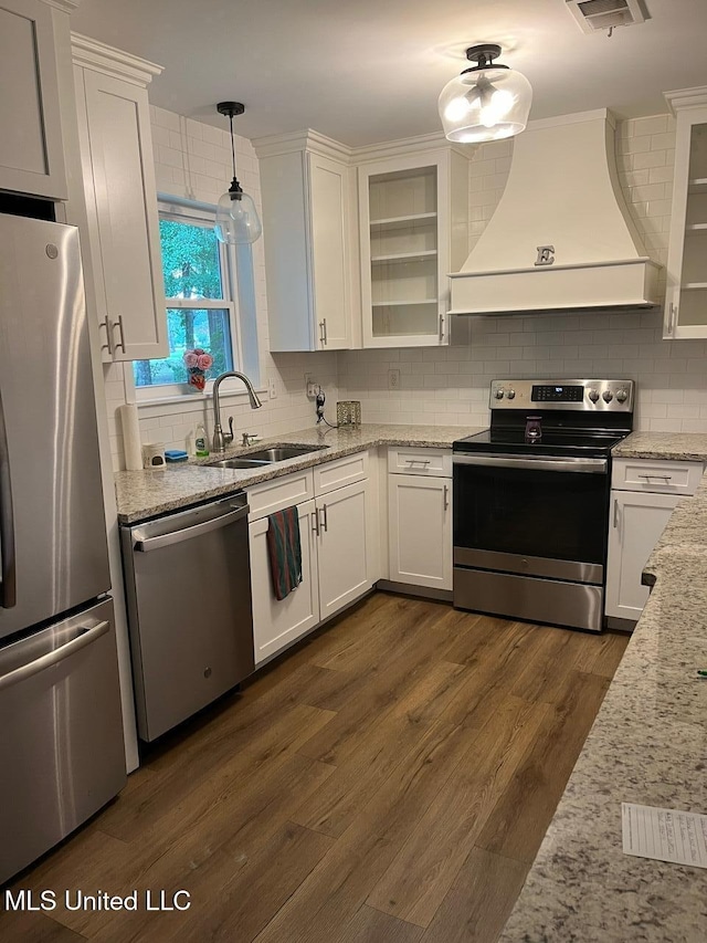 kitchen featuring appliances with stainless steel finishes, premium range hood, and white cabinetry