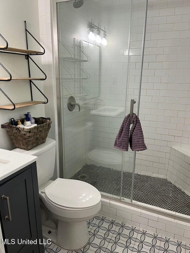 bathroom with toilet, a stall shower, tile patterned floors, and vanity