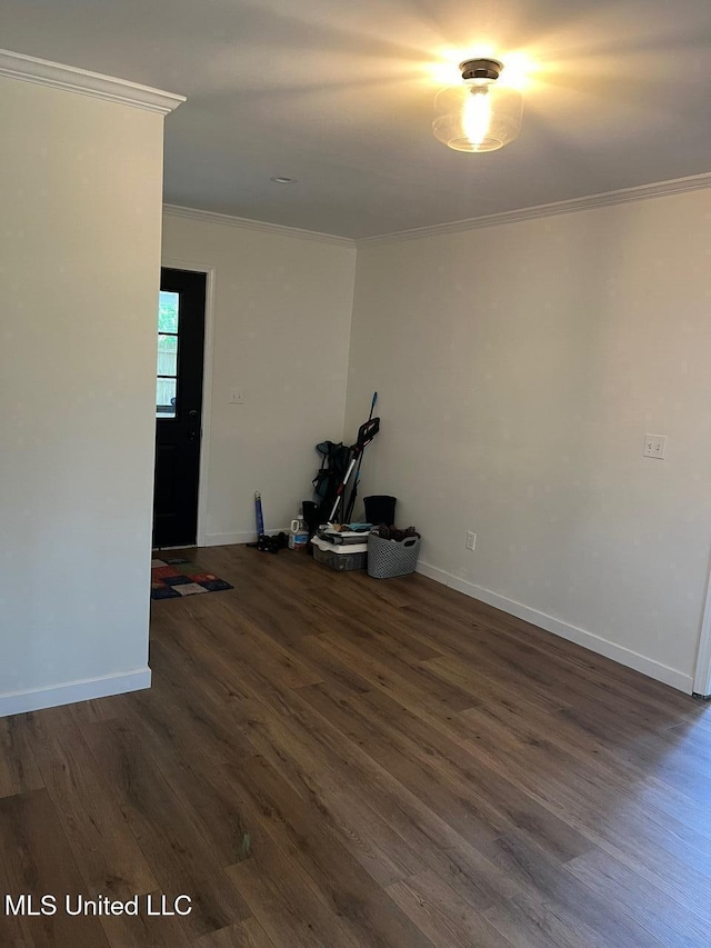 empty room featuring baseboards, ornamental molding, and dark wood-style flooring