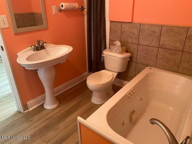 bathroom featuring toilet, wood-type flooring, and a bathing tub