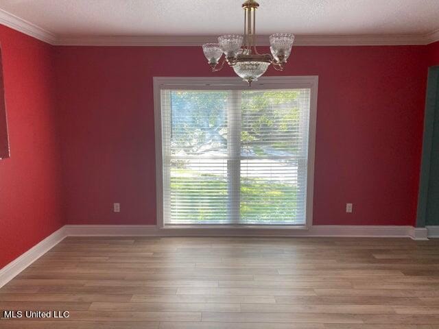 unfurnished dining area featuring a notable chandelier, a textured ceiling, wood-type flooring, and crown molding