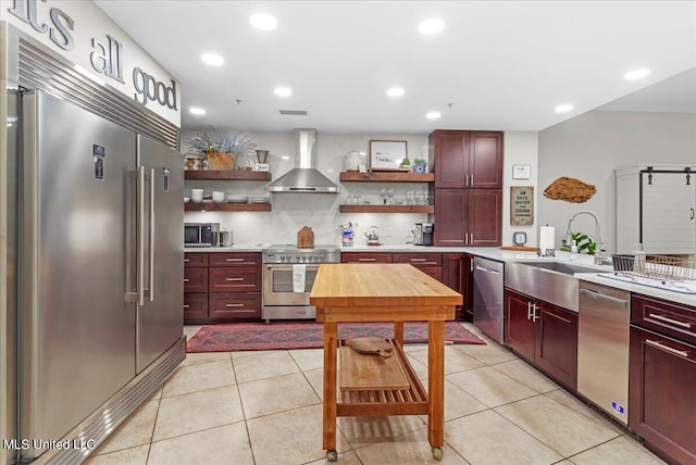 kitchen featuring wall chimney exhaust hood, stainless steel appliances, sink, light tile patterned floors, and tasteful backsplash