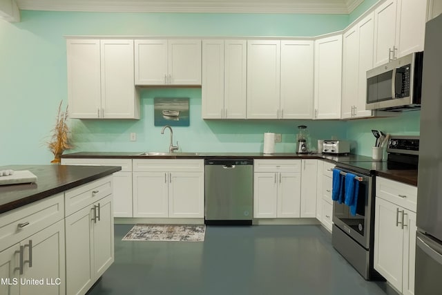 kitchen featuring crown molding, stainless steel appliances, dark countertops, white cabinets, and a sink