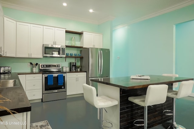 kitchen with stainless steel appliances, dark countertops, and white cabinets