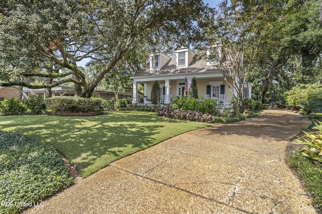 new england style home featuring covered porch and a front lawn