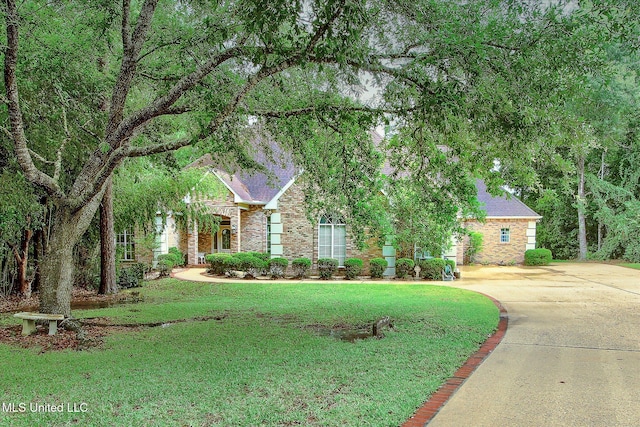 7622 Fairway Dr, Diamondhead, MS 39525 - view of property hidden behind natural elements with concrete driveway, a front lawn, brick siding, and roof with shingles