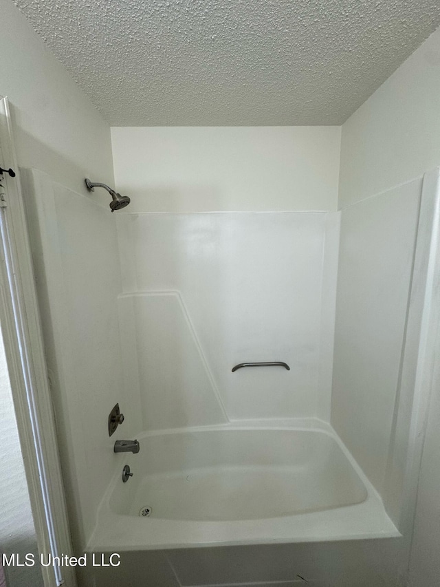 bathroom with shower / tub combination and a textured ceiling