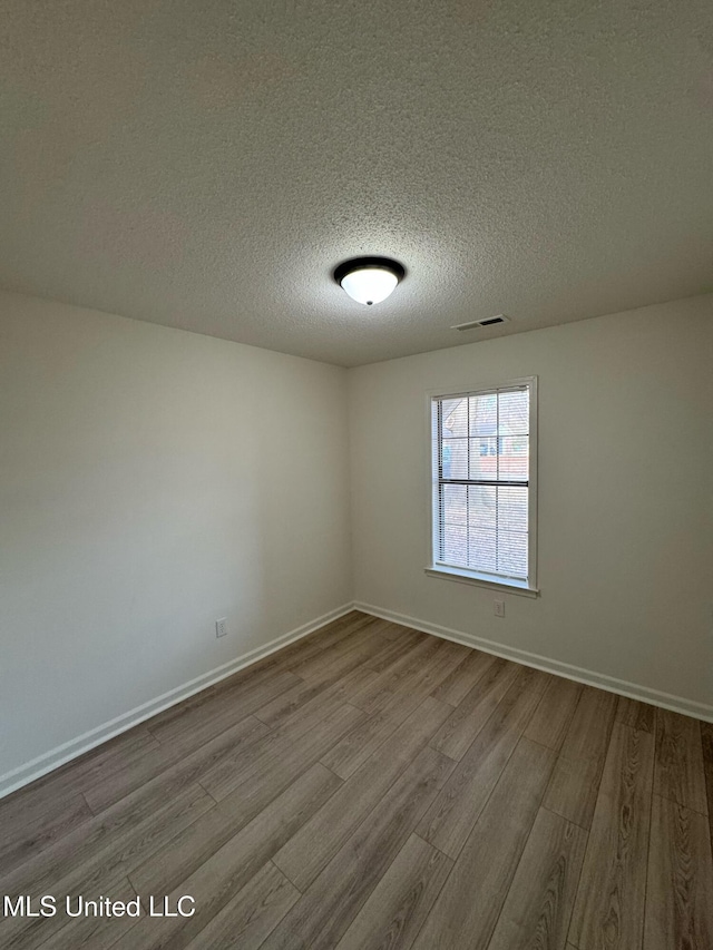 spare room featuring a textured ceiling and light wood-type flooring