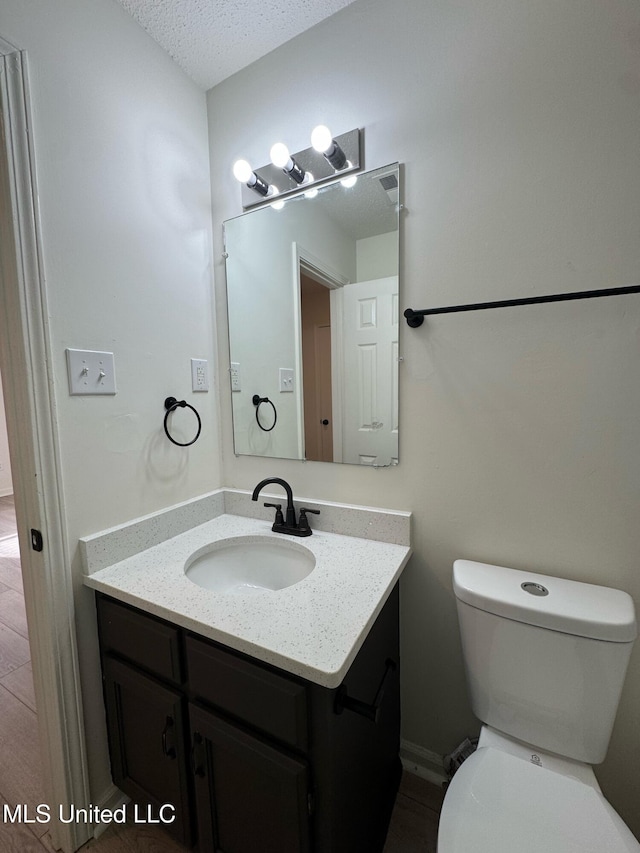 bathroom with vanity, a textured ceiling, and toilet