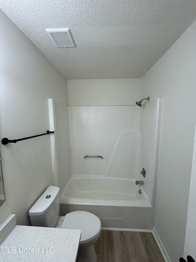 full bathroom with hardwood / wood-style flooring, tub / shower combination, vanity, a textured ceiling, and toilet