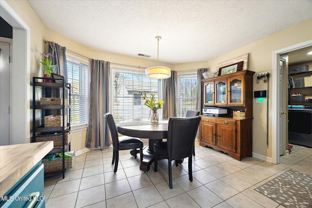 dining space featuring light tile patterned floors, a textured ceiling, visible vents, and baseboards