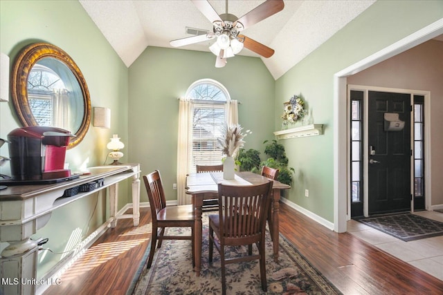 dining room featuring a textured ceiling, baseboards, vaulted ceiling, and wood finished floors