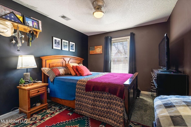 bedroom with a textured ceiling, carpet floors, visible vents, and baseboards