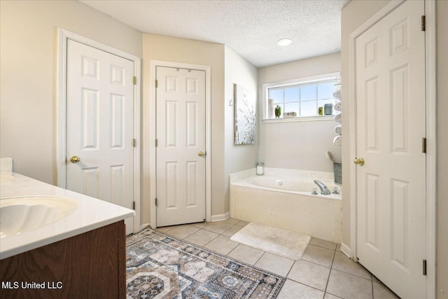 bathroom with tile patterned flooring, a garden tub, vanity, and a textured ceiling