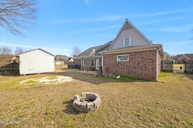 back of property with an outbuilding, brick siding, a lawn, and a fenced backyard