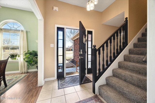 foyer featuring tile patterned flooring, stairs, and baseboards