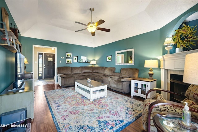 living room featuring lofted ceiling, ceiling fan, a fireplace, and wood finished floors