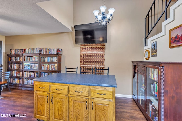 interior space with a notable chandelier, a textured ceiling, dark wood-type flooring, and a kitchen island