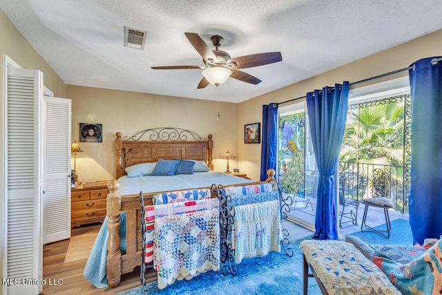 bedroom featuring ceiling fan, a textured ceiling, access to exterior, wood-type flooring, and a closet