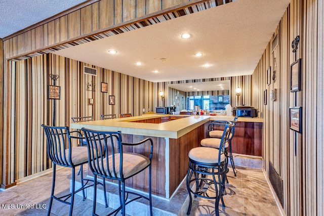 kitchen featuring a breakfast bar, a textured ceiling, and kitchen peninsula