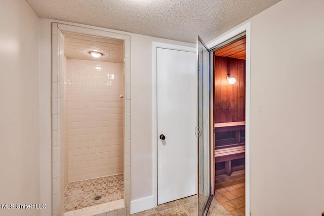 bathroom featuring a tile shower, a textured ceiling, and tile patterned floors