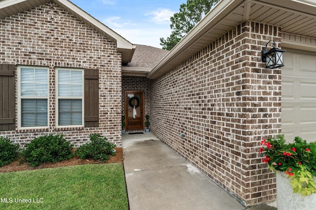 67 E Andover, Hattiesburg, MS 39402 - doorway to property featuring brick siding, a garage, and a shingled roof