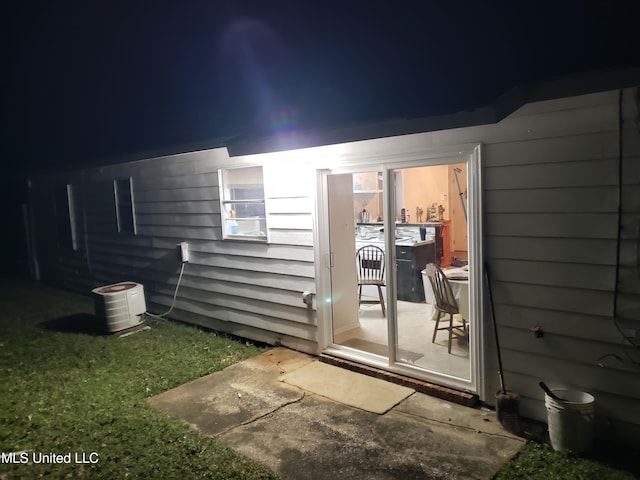 exterior entry at night featuring central air condition unit