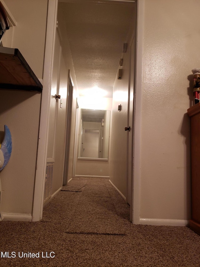 corridor featuring carpet flooring and a textured ceiling