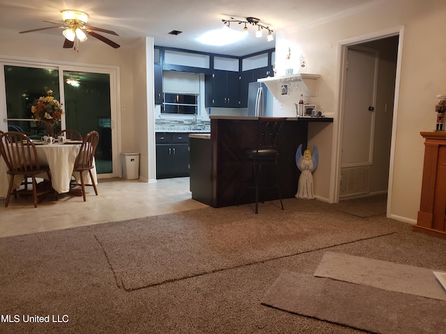 kitchen featuring a breakfast bar, ceiling fan, stainless steel fridge, ornamental molding, and kitchen peninsula