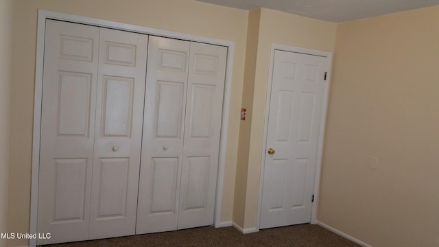 unfurnished bedroom with dark carpet and a closet