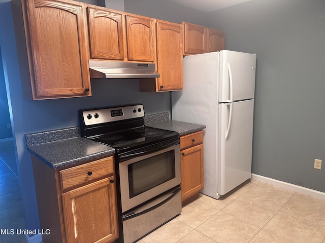 kitchen featuring white fridge, stainless steel electric range oven, and light tile patterned floors