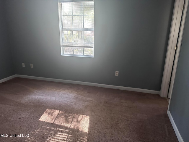 spare room featuring dark carpet