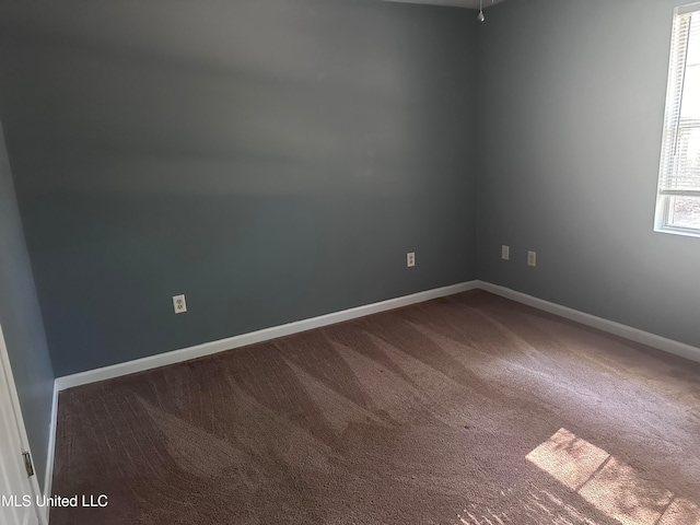 spare room featuring dark colored carpet