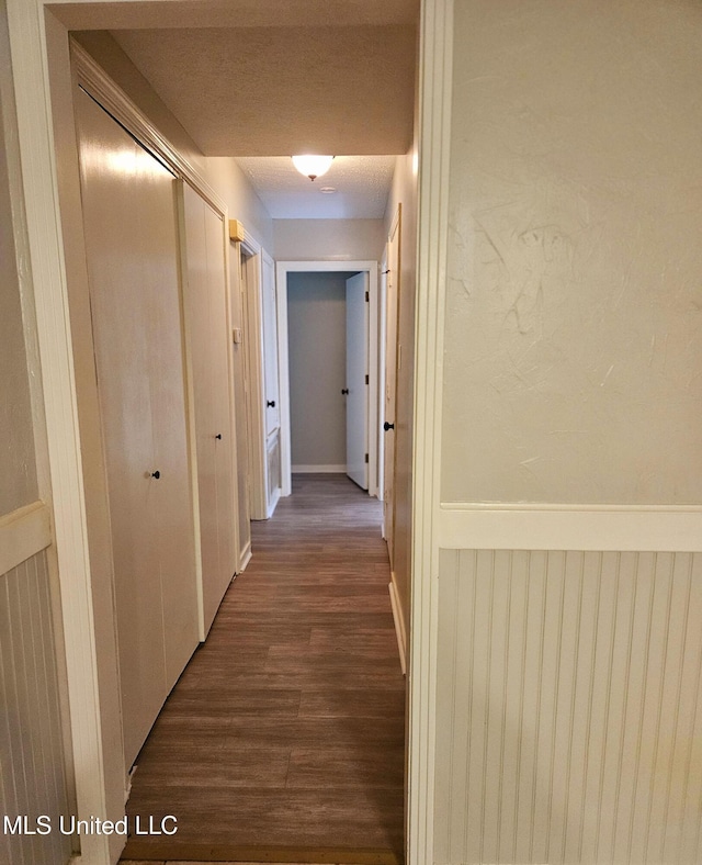 hall with dark wood-style floors and wainscoting