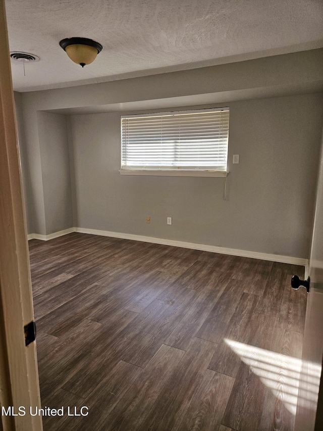 spare room with visible vents, baseboards, a textured ceiling, and wood finished floors