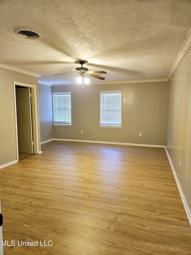 empty room featuring a textured ceiling, ornamental molding, and visible vents