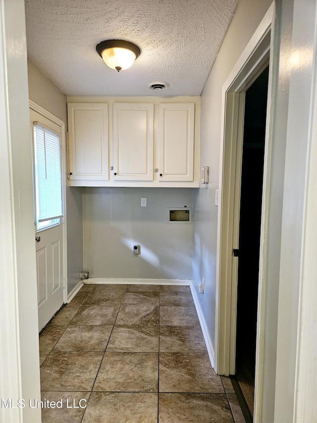 laundry area with a textured ceiling, baseboards, washer hookup, and cabinet space